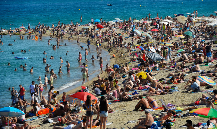 In this July 17, 2014 file photo, people relax on the beach, in Barcelona, Spain. Tourists and locals alike flock to beaches around the city, some of which are dotted with distinctive architecture.