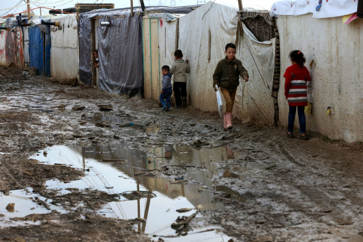 Syrian refugee children walk past tents at a refugee camp in the eastern Lebanese Town of Zahleh, Lebanon, Tuesday, Dec. 2.