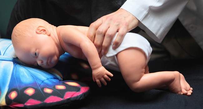 FILE- In this March 22, 2012 file photo, Dr. Wendy Gunther demonstrates how an infant can die due to unsafe sleeping practices using a scene re-enactment doll in Norfolk, Va.
