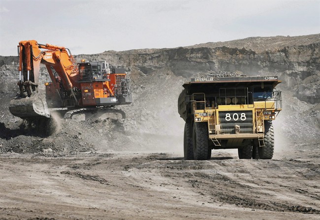 A haul truck carrying a full load drives away from a mining shovel at the Shell Albian Sands oilsands mine near Fort McMurray, Alta., Wednesday, July 9, 2008.