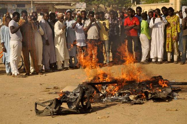 FILE- In this file photo taken on Friday, Nov. 28, 2014, People gather at the site of a bomb explosion in a area know to be targeted by the militant group Boko Haram in Kano, Nigeria.