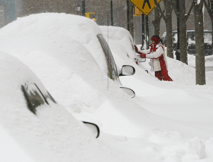 A girl wipes snow from a car during a fierce winter storm February 17, 2003 in New York City.