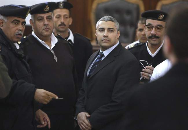 Canadian Al Jazeera English journalist Mohamed Fahmy, speaks with policemen during his retrial in Cairo, Egypt, Monday, Feb. 23, 2015. 