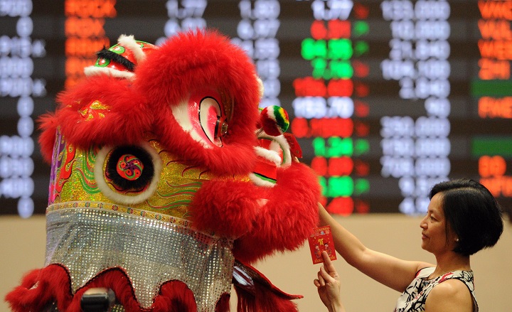 A performer donning a lion dance costume, tries to pick up red “lai see” envelopes from employees at the Philippine stock exchange during Lunar New Year of the Sheep celebrations in Manila on February 18, 2015.
