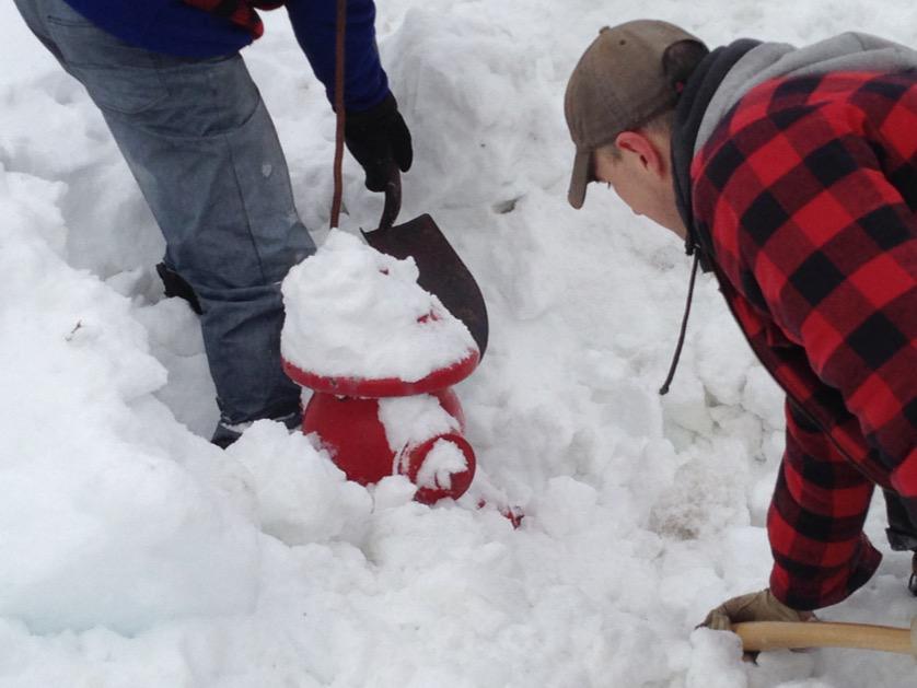 Off-duty firemen clear a fire hydrant covered in snow in Dartmouth.