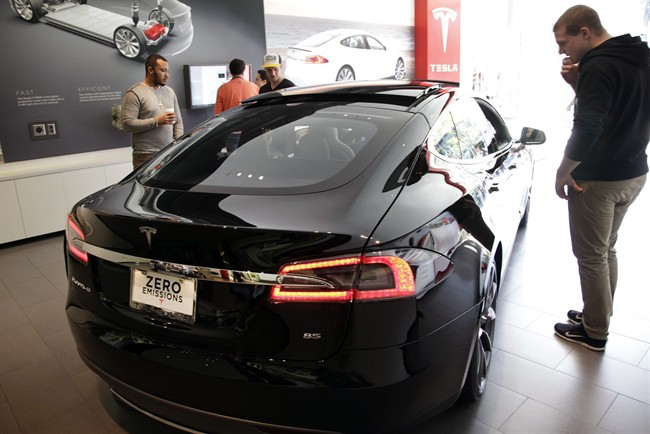 People check out the Tesla model S at the Tesla showroom at the the Third Street Promenade in Santa Monica, Calif. 