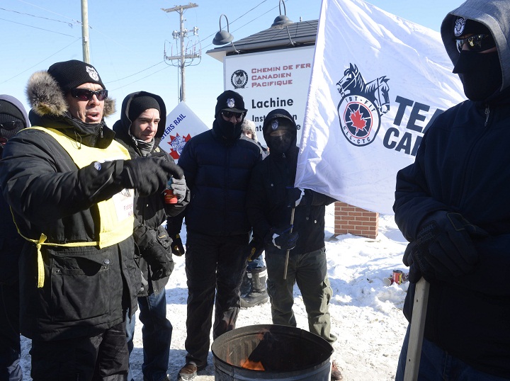 Canadian Pacific Railway workers huddle around a fire while on strike at the Cote Saint-Luc railyard in Montreal on Monday, Feb. 16, 2015.