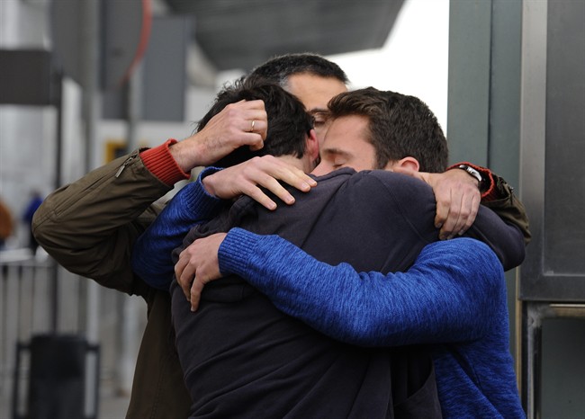 People comfort each other as they arrive at the Barcelona airport in Spain, Tuesday, March 24, 2015.