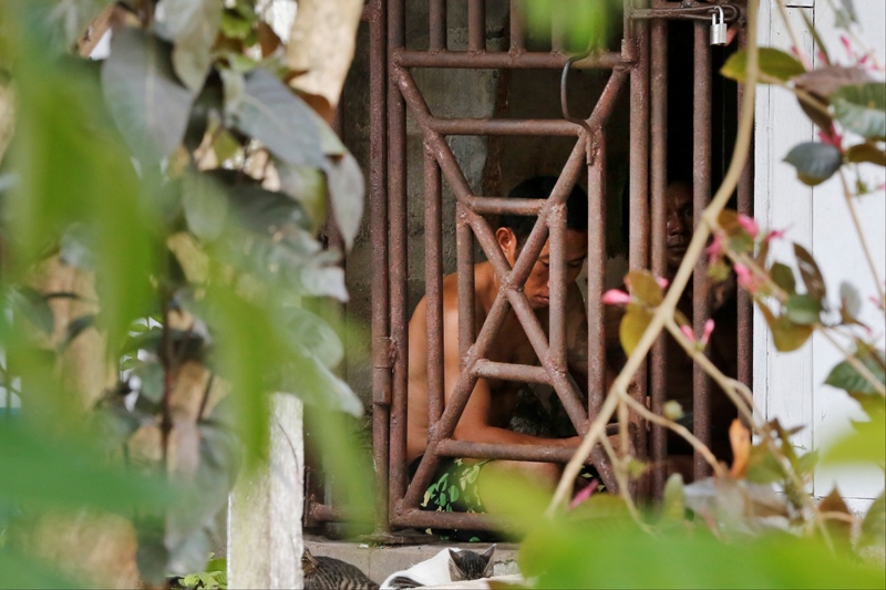 In this Saturday, Nov. 22, 2014 photo, Thai and Burmese fishing boat workers sit behind bars inside a cell at the compound of a fishing company in Benjina, Indonesia.