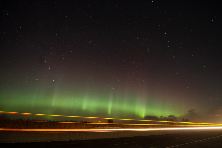 The aurora dance as a truck passes on the highway, north of Colborne, Ontario.