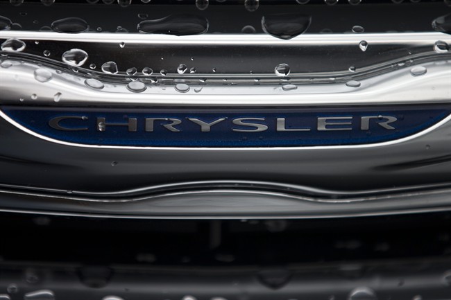 In this Dec. 2, 2014 photo, a Chrysler minivan sits under rain at a car lot in San Diego. Major automakers report vehicle sales for February on Tuesday, March 3, 2015. (AP Photo/Gregory Bull)