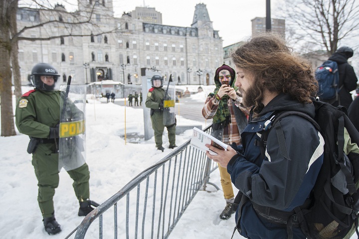 A protester reads poetry to a policemen during a protest against austerity organized by the ASSE student group in Quebec City, Thursday, March 26, 2015.