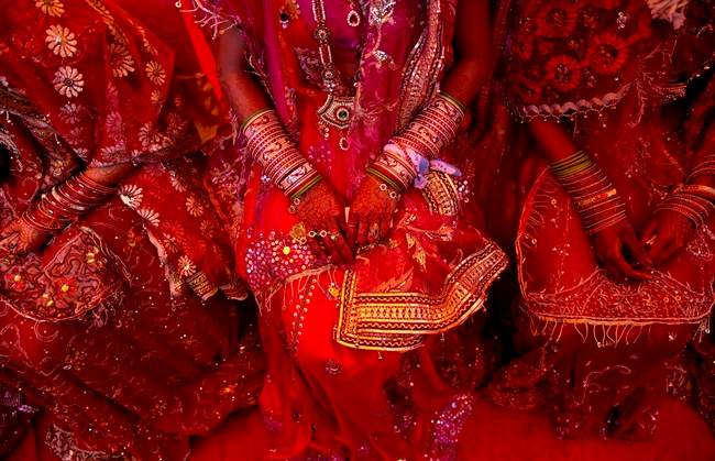 File photo showing Indian brides from impoverished families, dressed in wedding finery, wait for their grooms to arrive during a mass marriage ceremony in New Delhi, India.