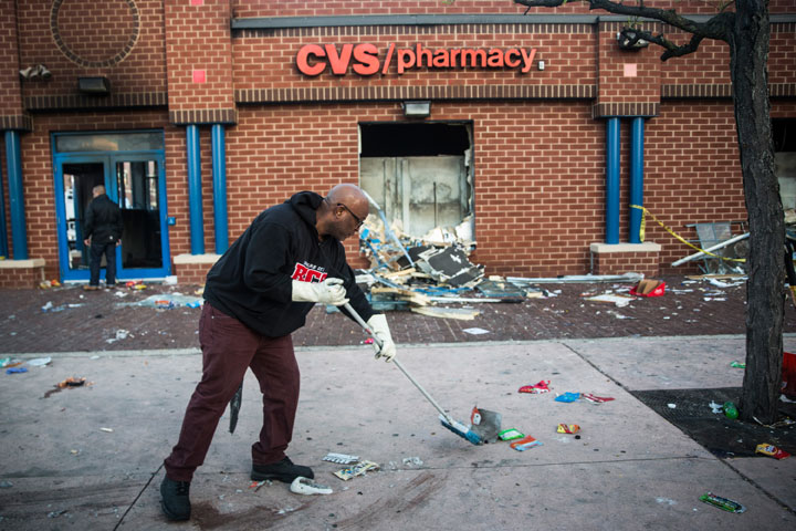 Jerald Miller helps clean up debris from a CVS pharmacy that was set on fire yesterday during rioting after the funeral of Freddie Gray, on April 28, 2015 in Baltimore,