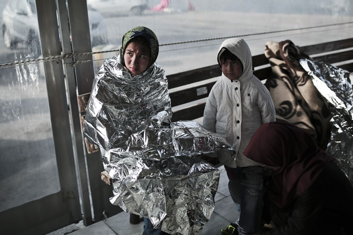 Immigrants gather in front of Hellenic coast guard as they arrive in the port on the island of Lesbos on April 18, 2015.