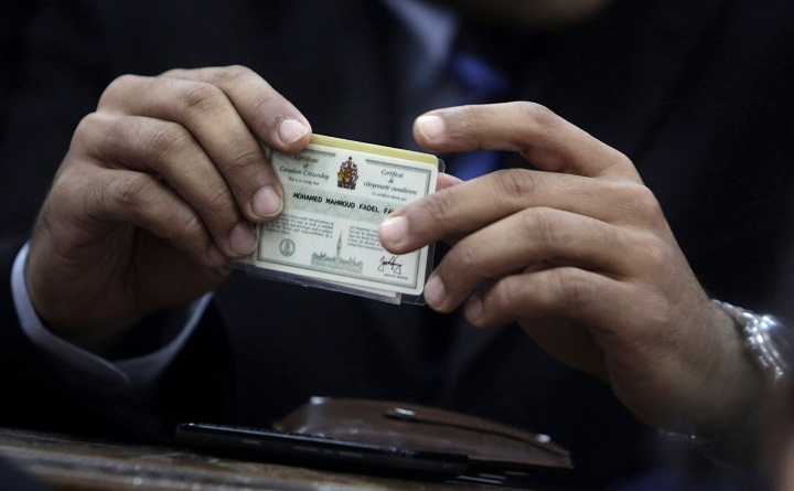 Canadian Al-Jazeera English journalist Mohamed Fahmy, holds his Canadian citizenship card as he attends his retrial at a court in Cairo, Egypt, Monday, Feb. 23, 2015.