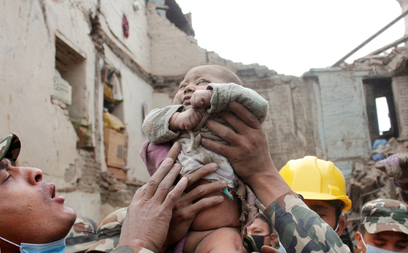 In this Sunday, April 26, 2015, photo taken by Amul Thapa and provided by KathmanduToday.com, four-month-old baby boy Sonit Awal is held up by Nepalese Army soldiers after being rescued from the rubble of his house in Bhaktapur, Nepal.