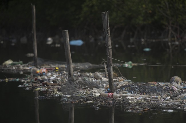 In this Feb. 28, 2015 file photo, trash floats on the water along a fence line in the Guanabara Bay in Rio de Janeiro, Brazil. The world governing body of sailing threaten Friday, April 24, 2015, to move events for the Rio 2016 Olympics out of the city\’s polluted Guanabara Bay unless \”a whole lot more is done very quickly\” to clear the venue of floating debris and sewage.