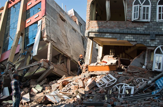 A rescue worker stands beside buildings that collapsed in an earthquake in Kathmandu, Nepal, Tuesday, May 12, 2015. A major earthquake has hit Nepal near the Chinese border between the capital of Kathmandu and Mount Everest less than three weeks after the country was devastated by a quake. (AP Photo/Ranup Shrestha).