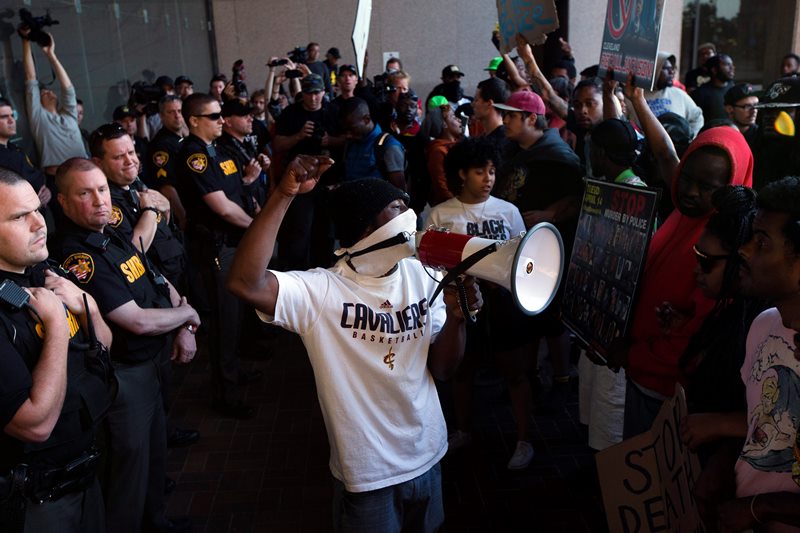 Demonstrators pause at the entrance to the Cuyahoga County Justice Center as police stand guard during a protest against the acquittal of Michael Brelo, a patrolman charged in the shooting deaths of two unarmed suspects, Saturday, May 23, 2015, in Cleveland. 