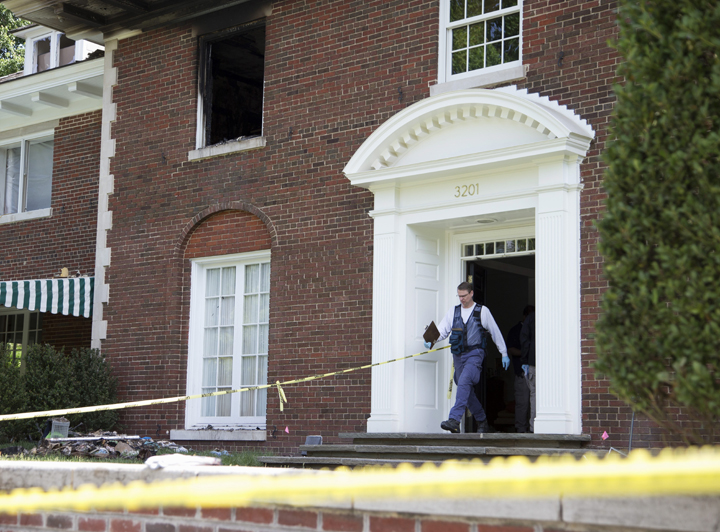 A Bureau of Alcohol, Tobacco, Firearms and Explosives investigator walks out of the fire-damaged multimillion-dollar home in northwest Washington, Wednesday, May 20, 2015, where four people were found dead May 14.