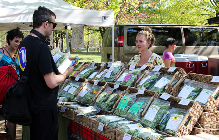A vendor at the Dufferin Grove Farmer’s Market in Toronto speaks to a customer.
