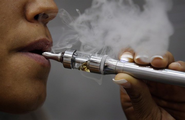 A woman smokes an electronic cigarette in Paris, Oct. 8, 2013. THE CANADIAN PRESS/AP, Christophe Ena