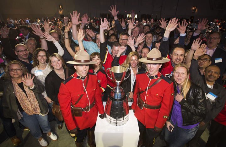 Shaw Communications employees celebrate with members of the RCMP and the Grey Cup during Shaw Communications/CFL partnership announcement in Calgary, Alberta, May 8, 2015.