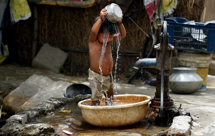 A young Indian child pours water on himself as he tries to cool himself off in New Delhi on May 28, 2015.