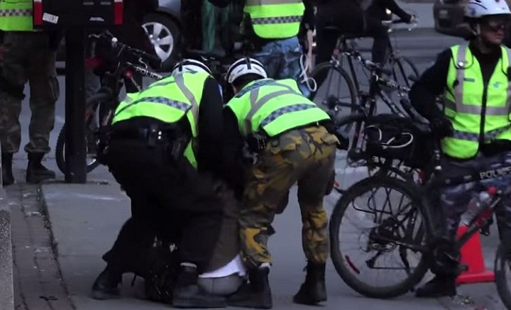 A still from a video that surfaced showing a man seemingly being hit in the face by Montreal police officers during May Day demonstrations.