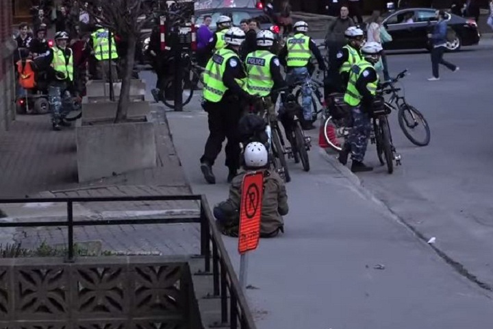 A still from a video that surfaced showing a man seemingly being hit in the face by Montreal police officers during May Day demonstrations.