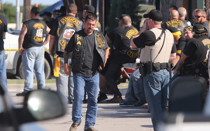 People stand as officers investigate a shooting in the parking lot of the Twin Peaks restaurant Sunday, May 17, 2015, in Waco, Texas. 