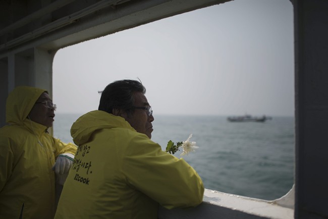 In this April 15, 2015, file photo, a relative of a victim of the ferry Sewol disaster watch the waters with flowers on the deck of a boat during a visit to the site of the sunken ferry, off the coast of South Korea\’s southern island of Jindo. It took divers in South Korea more than three agonizing days just to enter the ferry Sewol after it sank on April 16, 2014.