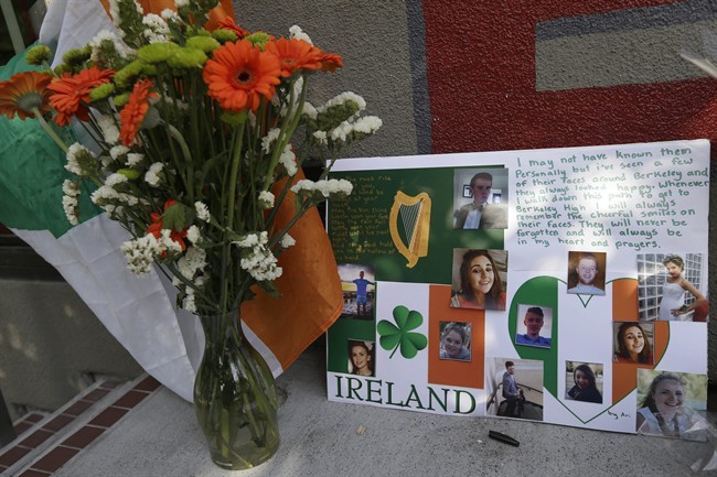 A flag of Ireland, flowers and a sign are shown at a shrine left for victims of the Library Gardens apartment building balcony collapse Wednesday, June 17, 2015. The balcony broke loose from the building during a 21st birthday party early Tuesday, killing several people and seriously injuring others.
