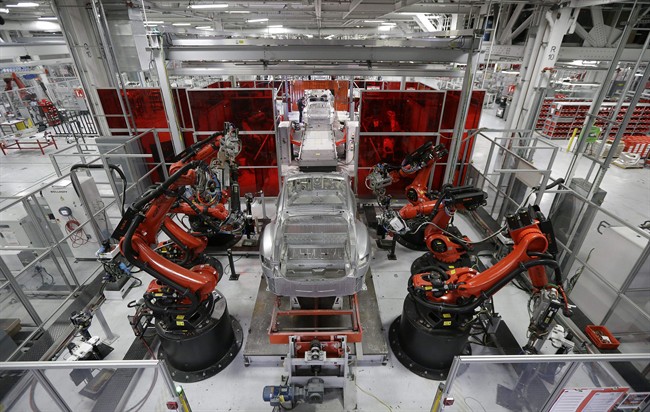 In this May 14, 2015 photo, Kuka robots work on Tesla Model S cars in the Tesla factory in Fremont, Calif.