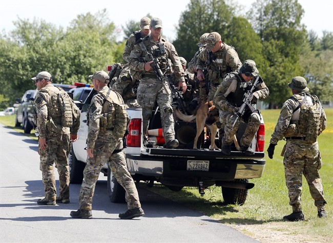 Law enforcement officers get off a truck as they return to their vehicles after searching a wooded area on Sunday, June 14, 2015, in Schuyler Falls,