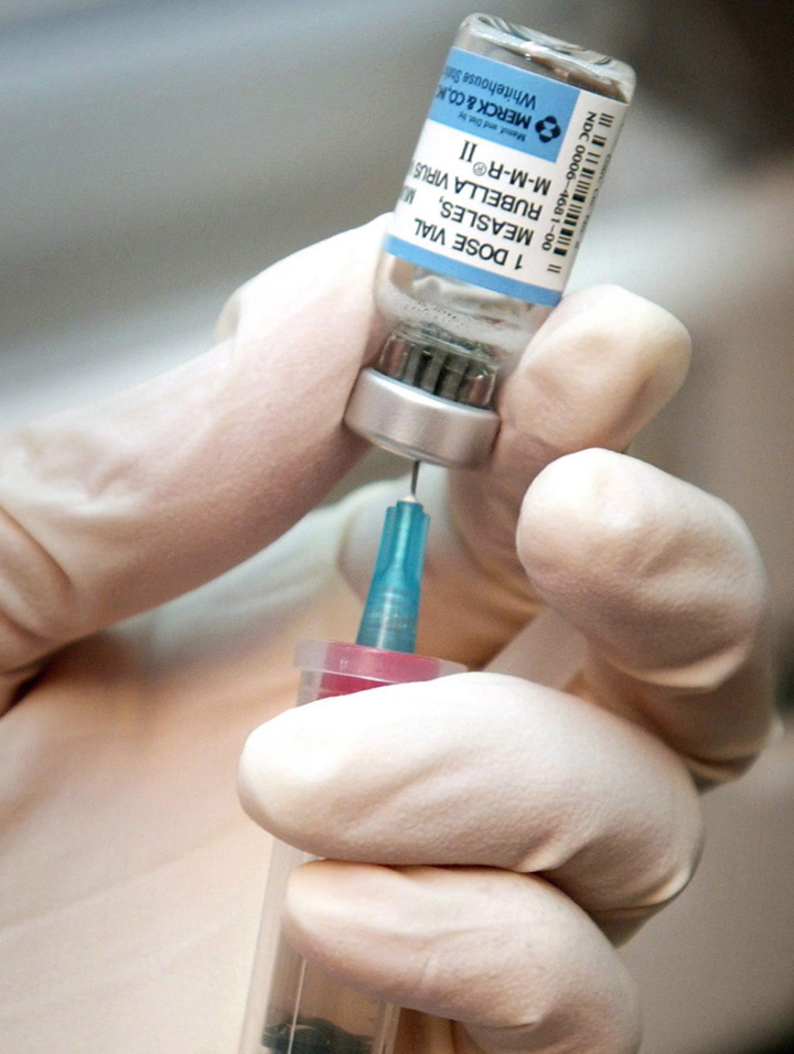 A nurse draws a dose of mumps, measles, and rubella vaccine.