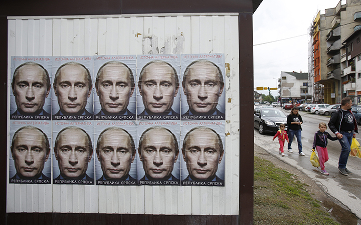 People pass by posters displaying Russian President Vladimir Putin in the town of Bratunac, near Srebrenica on Sunday June, 28, 2015, less than two weeks before the Srebrenica massacre's 20th anniversary.