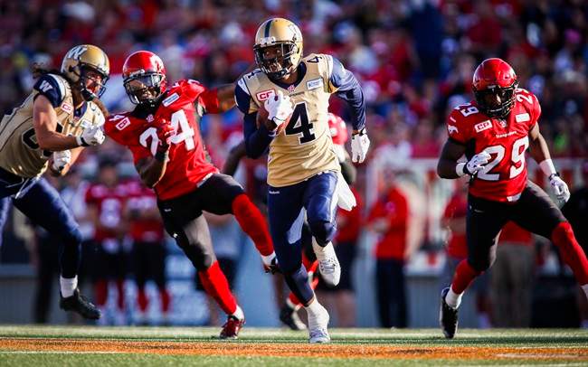 Winnipeg Blue Bombers' Darvin Adams, centre, runs the ball in for a touchdown as Calgary Stampeders' Joe Burnett, (24) and Jamar Wall (29) look on during second half CFL football action in Calgary, Saturday, July 18, 2015.