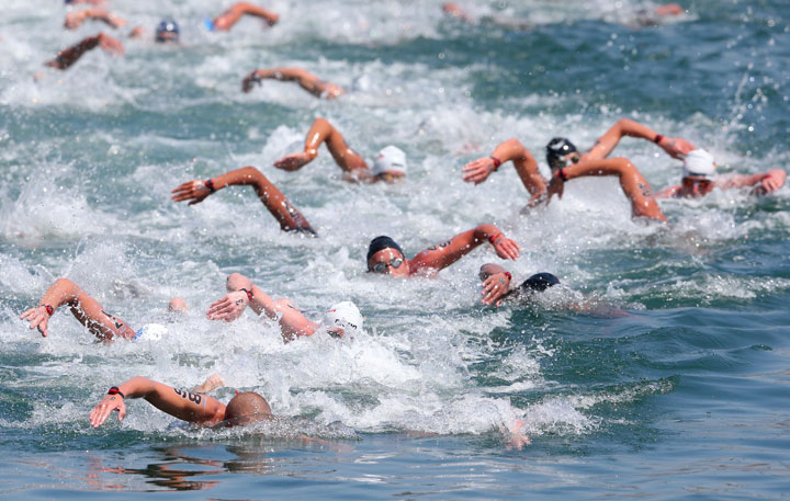 Richard Weinberger #86 of Canada and Damien Cattin-Vidal #32 of France lead a group of swimmers during the Open Water Swimming Men's 10k race on day three of the 15th FINA World Championships at Moll de la Fusta on July 22, 2013 in Barcelona, Spain.