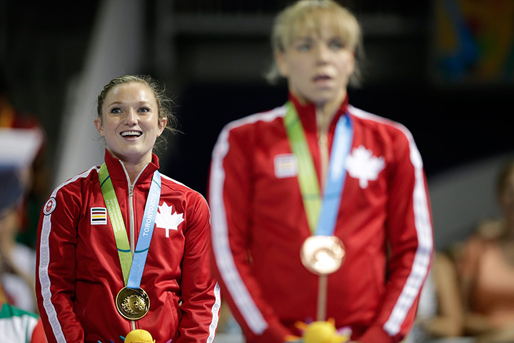 Canada’s Rosie MacLennan, left, and teammate Karen Cockburn listen to the national anthem after women’s trampoline competition in the Pan Am Games in Toronto Sunday, July 19, 2015.