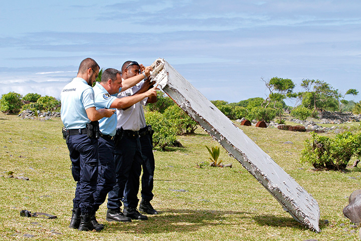 In this photo dated Wednesday, July 29, 2015, French police officers inspect a piece of debris from a plane in Saint-Andre, Reunion Island.