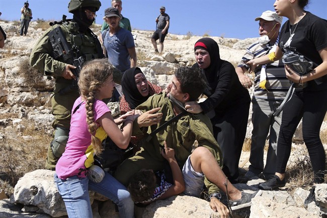 In this Friday, Aug, 28, 2015 photo, Palestinian women and youth scuffle with an Israeli soldier trying to arrest a 12-year-old boy during a protest near the West Bank village of Nebi Saleh.