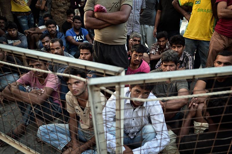 Migrants wait outsie the police station which serves as their registration center in the town of Kos at the southeastern Greek island of Kos, on August 15, 2015.