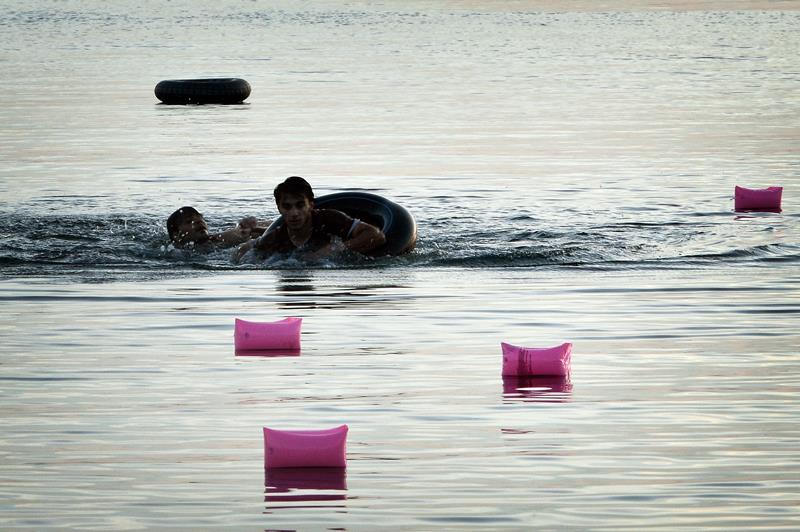 Syrian migrants swim towards the beach after arriving on an overcrowded dinghy to the Greek island of Kos, on August 15, 2015.