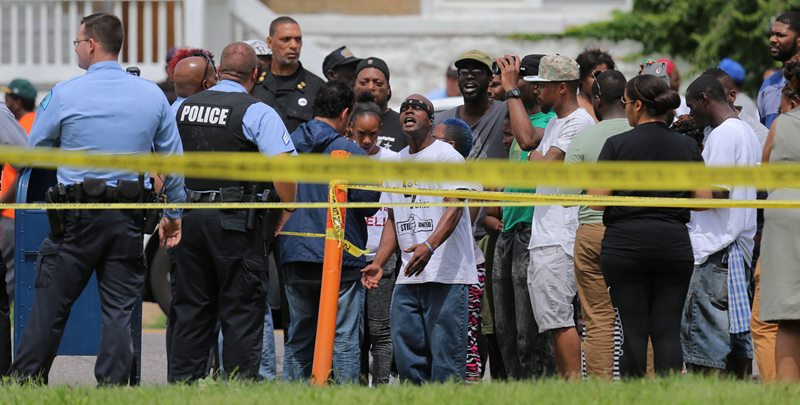 People confront police at the scene of a fatal officer-involved shooting at Walton Avenue and Page Boulevard on Wednesday, Aug. 19, 2015 in St. Louis. An armed man fleeing from officers serving a search warrant at a home in a crime-troubled section of north St. Louis was shot and killed Wednesday by police after he pointed a gun at them, the police chief said. 