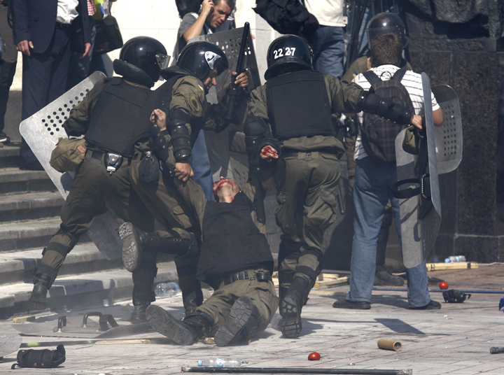 Police officers carry their injured colleague after grenade exploded during a clash between protesters and police after vote to give greater powers to the east, outside the Parliament, Kiev, Ukraine, Monday, Aug. 31, 2015.  (AP Photo/Vladimir Donsov)