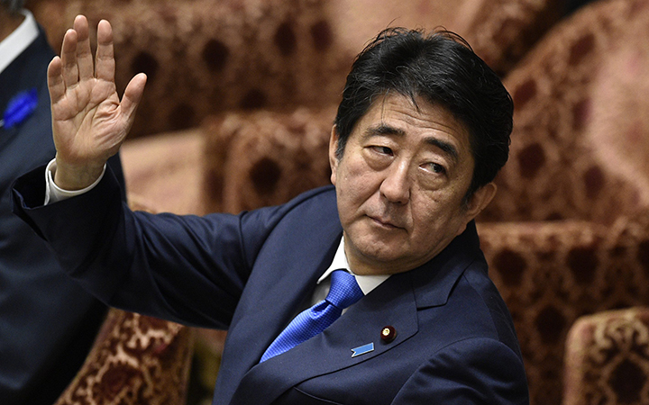 Japanese Prime Minister Shinzo Abe raising his hand before answering a question from a lawmaker during a committee session debating the security bills at the parliament in Tokyo, Japan. 