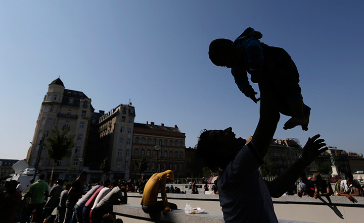 A migrant holds up a baby in front of the Keleti Railway Station in Budapest, Hungary, Wednesday, Sept. 2, 2015, as hundreds demanded to be let on trains to Germany.