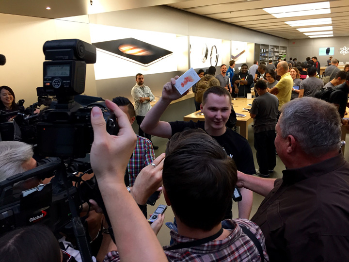 The first customer to purchase an iPhone 6S at the Toronto Eaton Centre shows off his purchase to media.